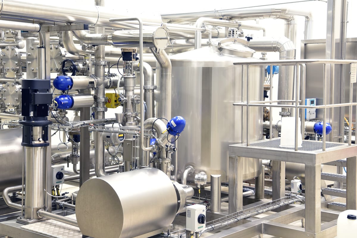 Innenansicht einer Industrieanlage mit Rohrleitungen und Lagertank